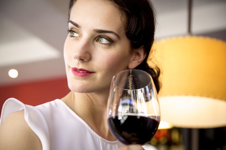 Frau mit einem Glas Rotwein in der Hand