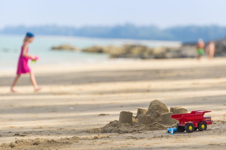 Kind und Kinderspielzeug am Sandstrand