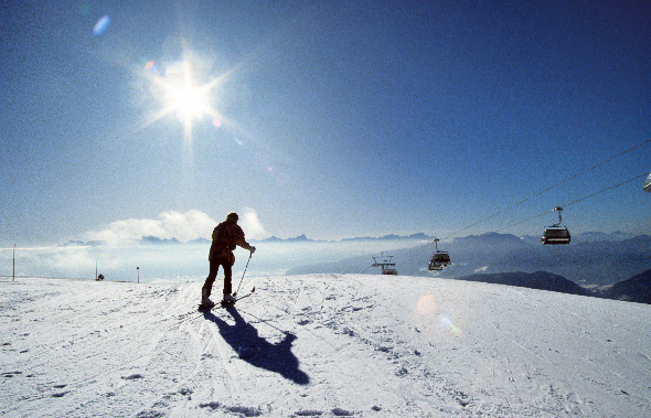 Mann fährt ski und die Sonne strahlt kräftig auf die Piste