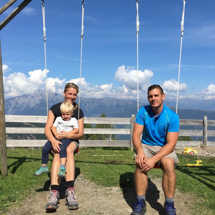 Eltern mit Kind auf Schaukel in den Bergen