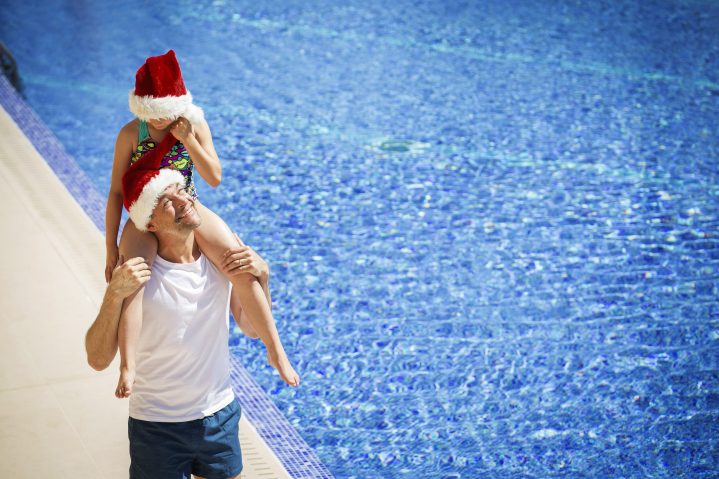 Vater und Tochter mit Weihnachtsmütze am Pool