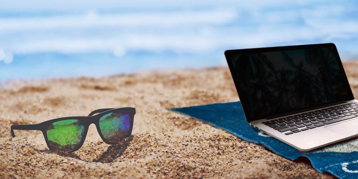 Laptop und Sonnenbrille am Strand