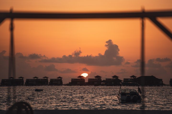 Speedboat vor Wassernbungalows bei Sonnenuntergang
